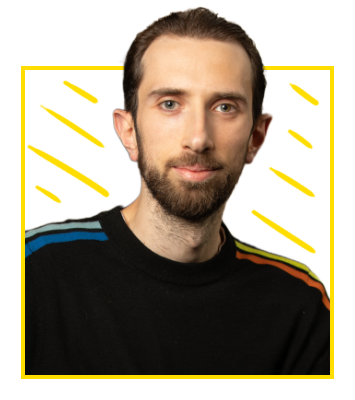 Headshot: a white man with dark hair and a short dark beard. He is wearing a black jumper with colourful stripes running down the shoulders.